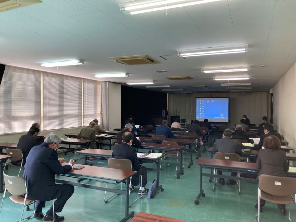スクリーンに資料を映し壇上で説明をする方と席に座り聞いている参加者の方々の写真