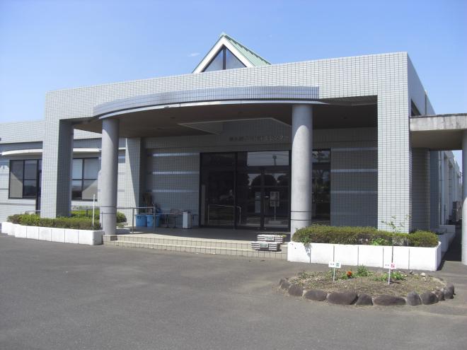 四角いグレーの外観で周りには植木などが植えられた南九州市頴娃保健センター入口付近の写真