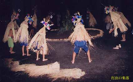 中央に神籬が置かれた土俵の周りを腰まで隠れるほどの長さの藁の笠をかぶった子供たちが囲んでいる打出口集落の十五夜ソラヨイの様子の写真