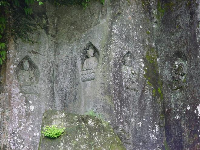 道路脇の崖の石面に彫られた、合計4体の仏像と天照大神像がある高田磨崖仏の写真