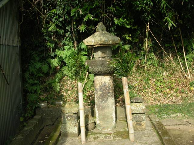 両脇に竹の棒に飾られた榊が備えられている石造りの大きな七観音塔の写真