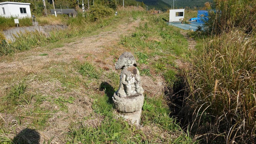 土手部分に鎮座する石造の田の神像