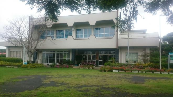 建物前にはプランターに植えた花や木が植えられ、白い外壁で中央部分が2階建ての御領地区公民館の外観写真
