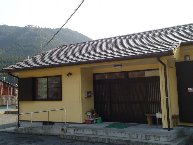 薄黄色の外壁で、中央に入り口があり左側にスロープが設置されている田代地区公民館の建物外観の写真