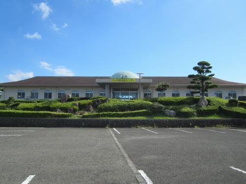 きれいに剪定された植木が手前に広がっており、奥には正面入り口の上部に黄色の看板が設置されている「えい別府温泉センター」の外観写真