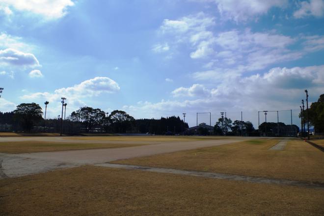 バックネットと夜間照明が設置され、広々とした芝生の広場が広がっている南九州市知覧平和公園陸上競技場の写真