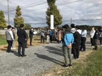 新庁舎の建設予定地に集まり、男性の話を聞く参加者の写真