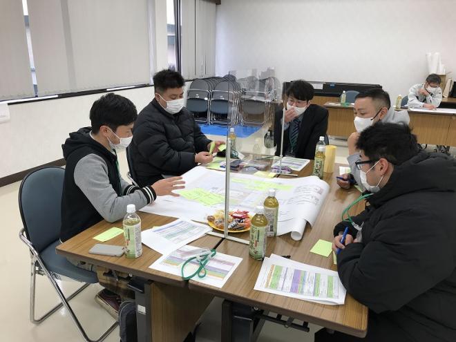 意見が書かれた付箋が模造紙に沢山貼られており、1人の男性が話をしているグループ意見交換の様子の写真