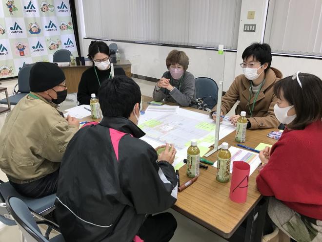 意見が書かれた付箋が模造紙に沢山貼られており、グループで意見交換が行われている様子の写真