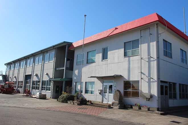 2階建ての建物が2棟並び、旗ポールが1本立っている松元機工株式会社の写真