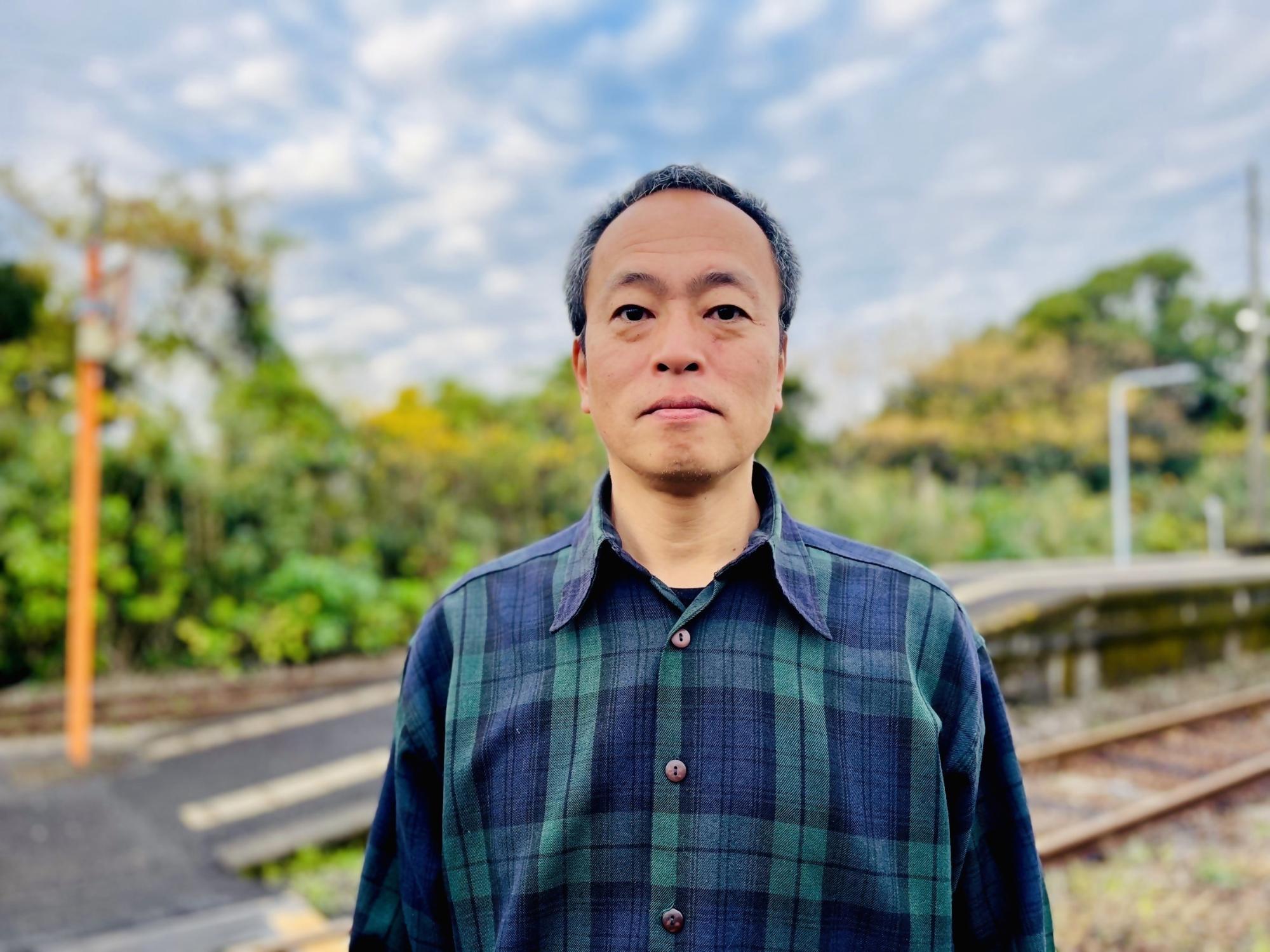 JR西頴娃駅のホーム前に立つ地域おこし協力隊の小野寺宗貴さんの写真