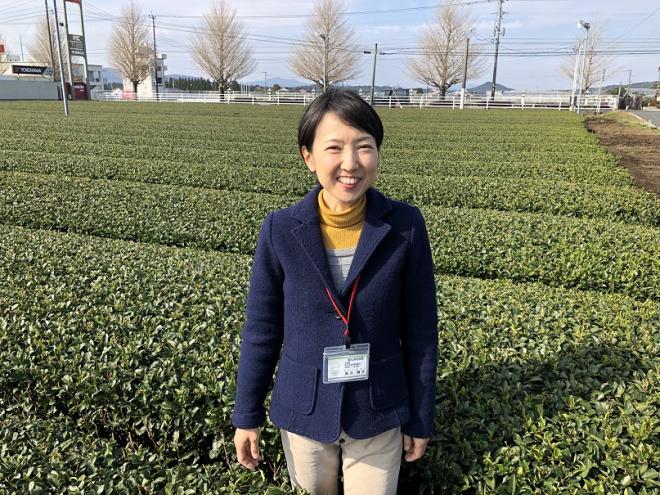 茶畑の中で笑顔で立っている南九州市地域おこし協力隊・高久博子さんの写真