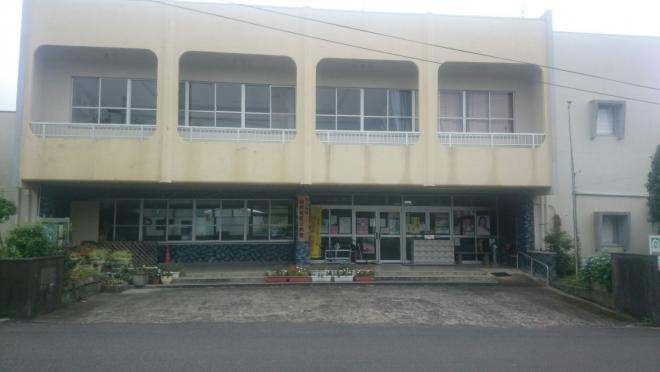 クリーム色の外壁の2階建ての建物で、2階部分はベランダが設けられている別府地区公民館の外観写真