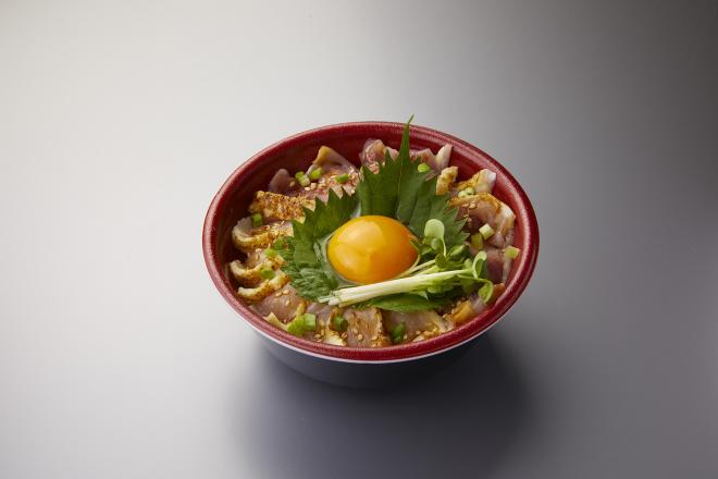 どんぶりに鳥刺しがきれいに並べられ、中央の大葉の上に生の卵黄とかいわれ大根が添えられたそのだストアーの名物丼の写真