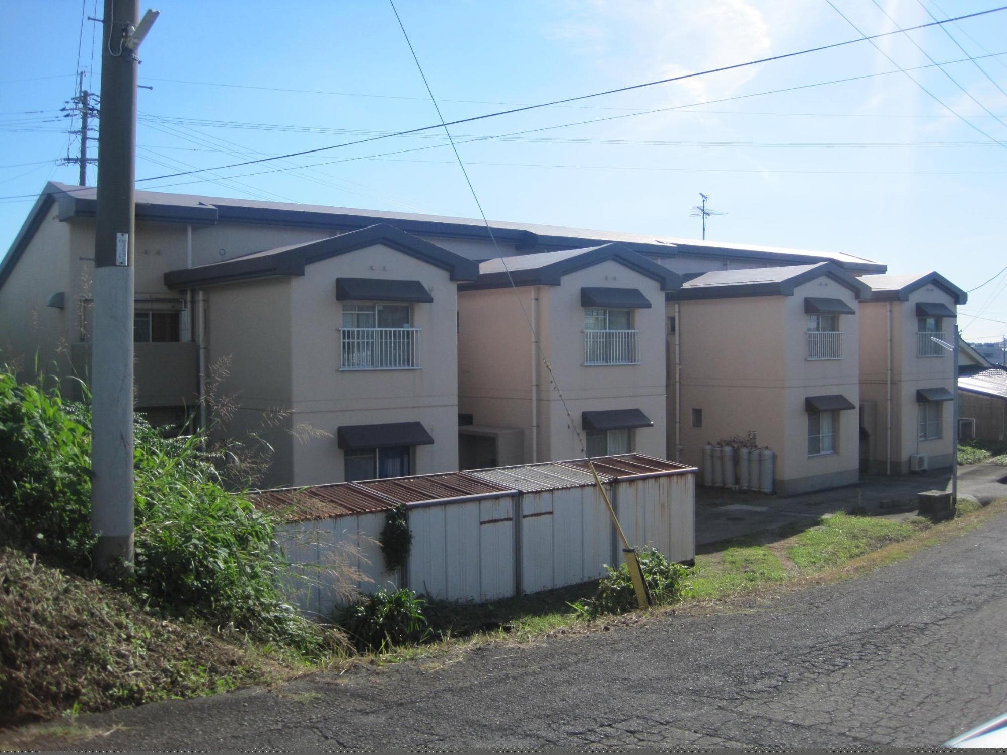 少し高い位置にある道路から横長の2階建て市営住宅 公営三俣団地の外観を写した写真