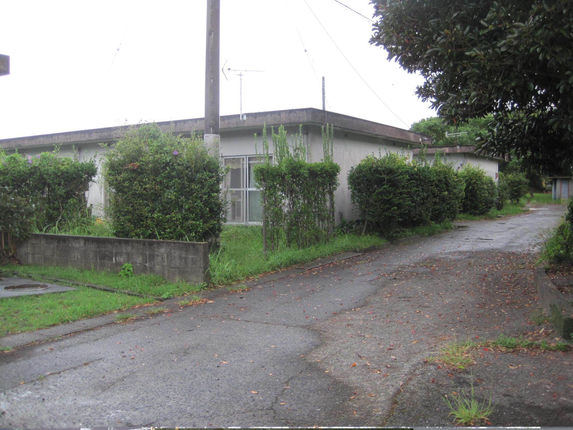 屋根が平らで1階建ての市営住宅 公営吟ノ場団地が植栽の間から見えている写真