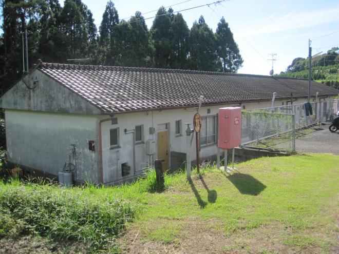 建物後方に杉の木が生えている三角屋根1階平屋建ての市営住宅 公営粟ヶ窪団地の写真
