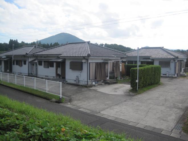 住宅敷地と道路の間に白いフェンスがあり、白い外壁瓦屋根の家が3軒写っている市営住宅 公営御領団地の写真
