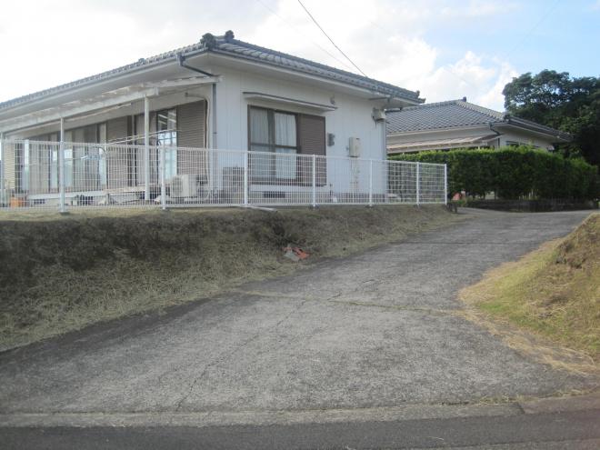 緩やかな坂を上った左側の白いフェンスの奥に、白い外壁で瓦屋根の住宅が建っている市営住宅 特公賃御領団地の写真