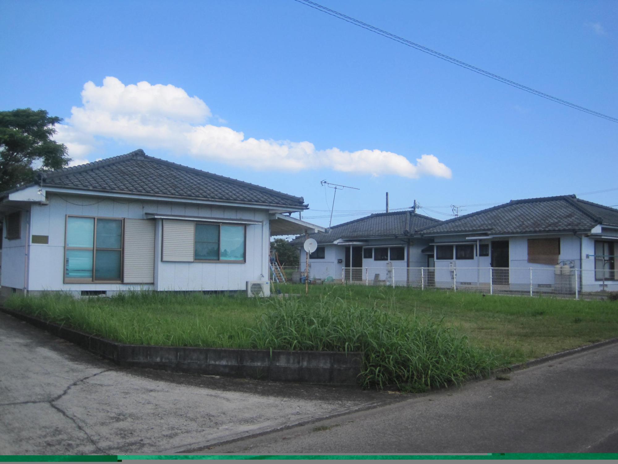 方形屋根をした白い外壁の住宅が手前に1軒、右奥に2軒並んでいる市営住宅 公営耳原団地の写真