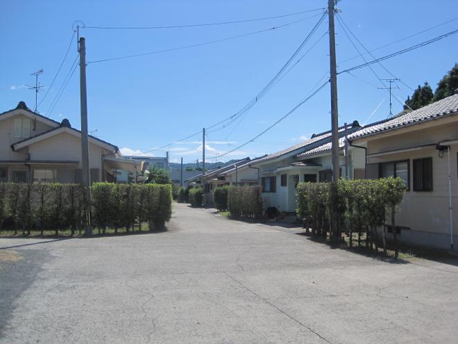 通路の両側の垣根の奥に1階建ての住宅が複数並んでいる市営住宅 特公賃西頴娃団地の写真