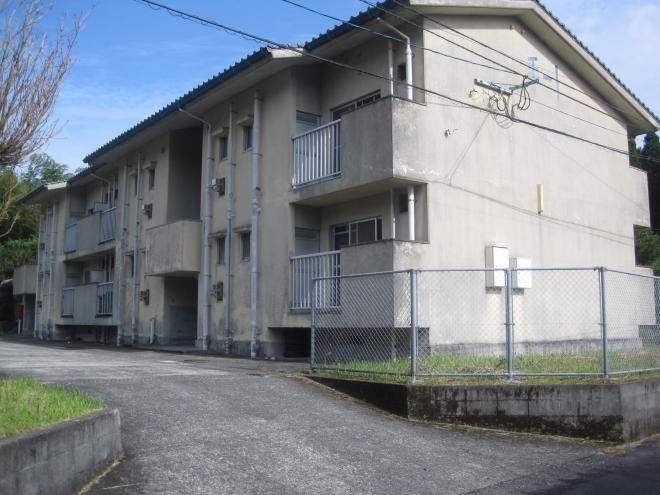 団地の敷地入口部分が少し坂になっており、右側に三角屋根2階建ての建物が建っている市営住宅 公営手蓑団地の写真