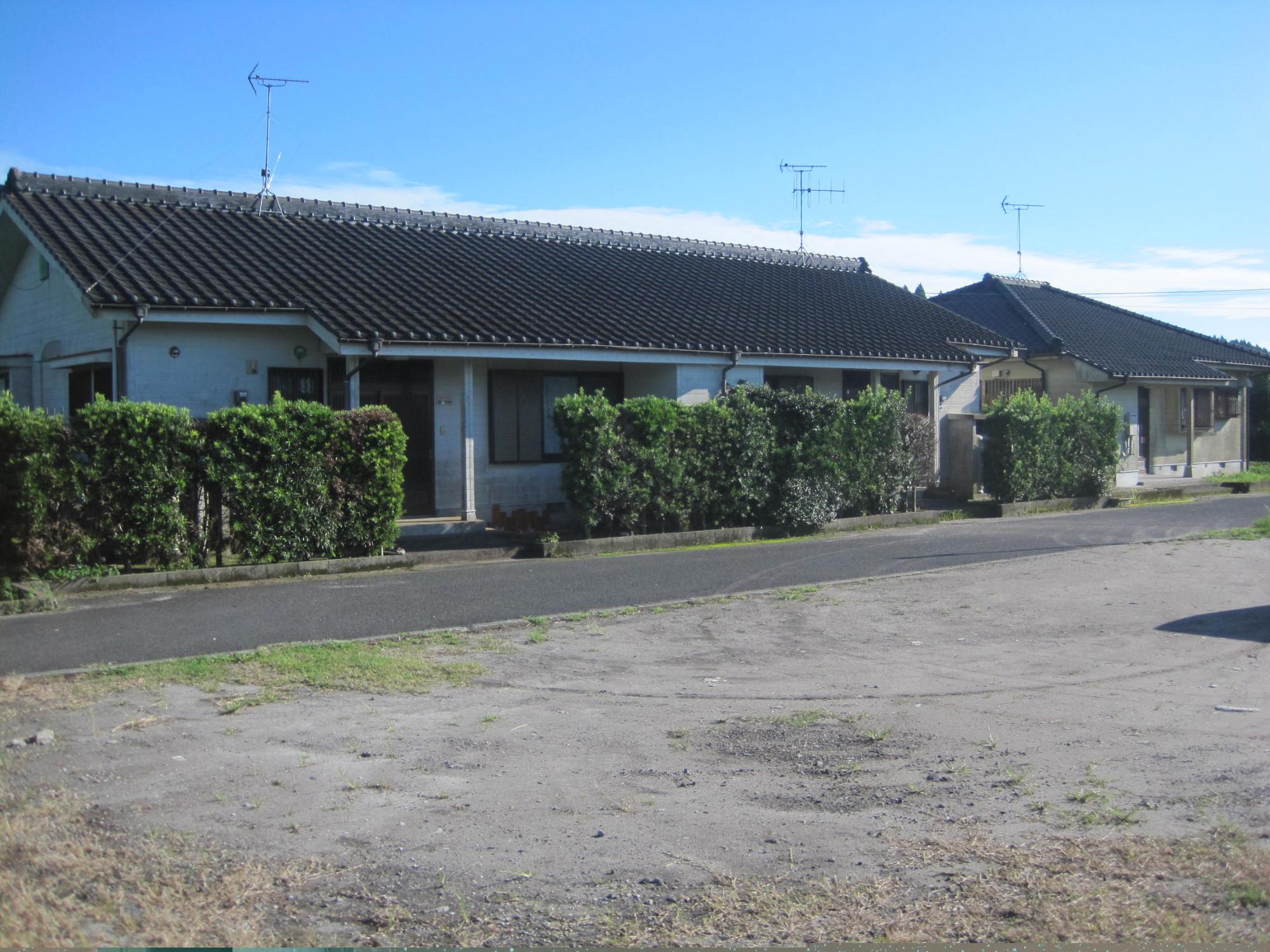 建物手前に垣根があり、横長で、三角瓦屋根の市営住宅 一般松木団地の写真