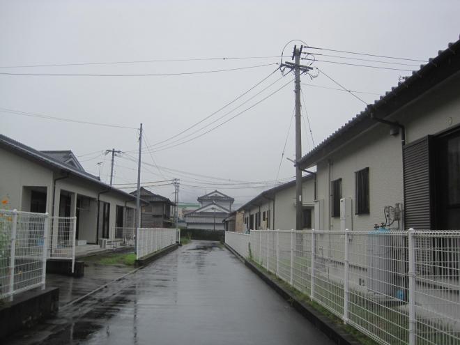 白い格子状のフェンス内に瓦屋根平屋建て住宅が通路の両側に建っている市営住宅 公営諏訪下団地の写真