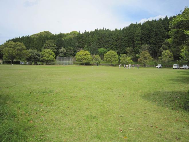整備された広い芝生が広がり、奥に木々が生い茂った山が見える岩屋公園の写真