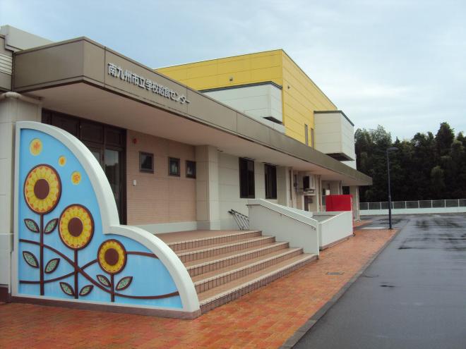 入口の階段横の壁にヒマワリが描かれている、南九州市立学校給食センターの外観写真写真