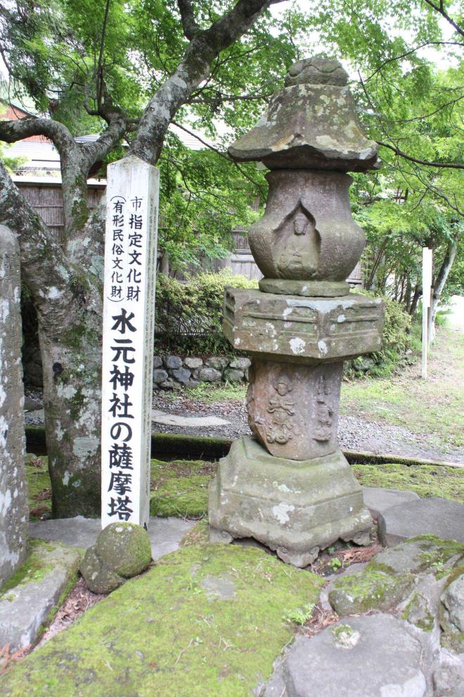 水元神社境内に設置された、須弥壇部に四天王像、壺型の塔身に如来坐像が彫られている六角形の石塔と、横に設置された市指定文化財（有形民俗文化財）水元神社の薩摩塔と書かれた白い標柱