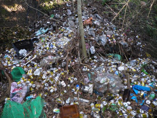 山に大量の缶が拡散され、針金のネット、燃えないゴミが不法投棄されている写真