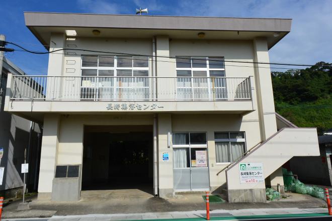 白壁で2階へ上がる外階段のある長崎集落センターの建物外観の写真