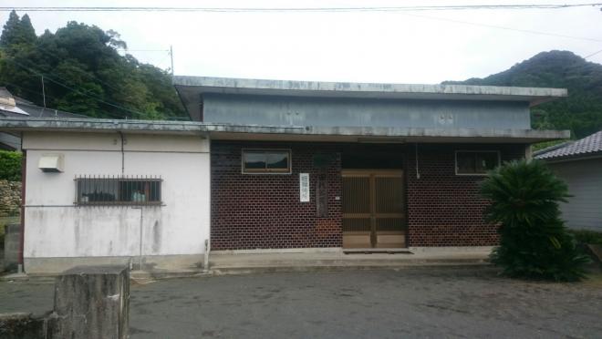 四角い平屋建ての建物で、クリーム色とえんじ色のタイル調の外壁をした田代区公民館の外観写真