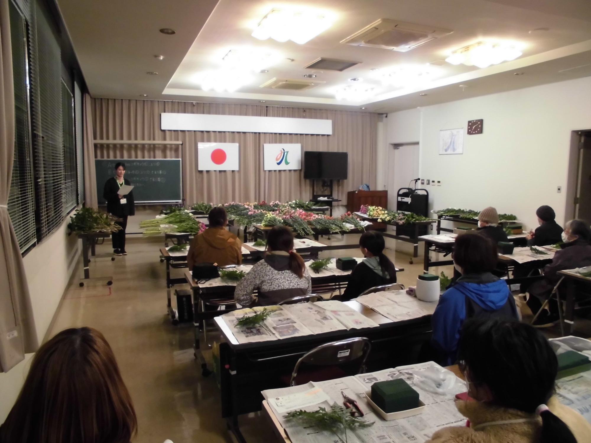 フラワーアレンジメント創作会で参加者にイベント内容を説明する様子