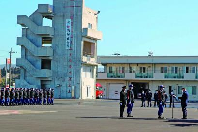 「祝消防出初式」の垂れ幕がかかった訓練用の建物の手前にたくさんの消防職員・団員が整列し、右前方では表彰式が行われている様子の写真